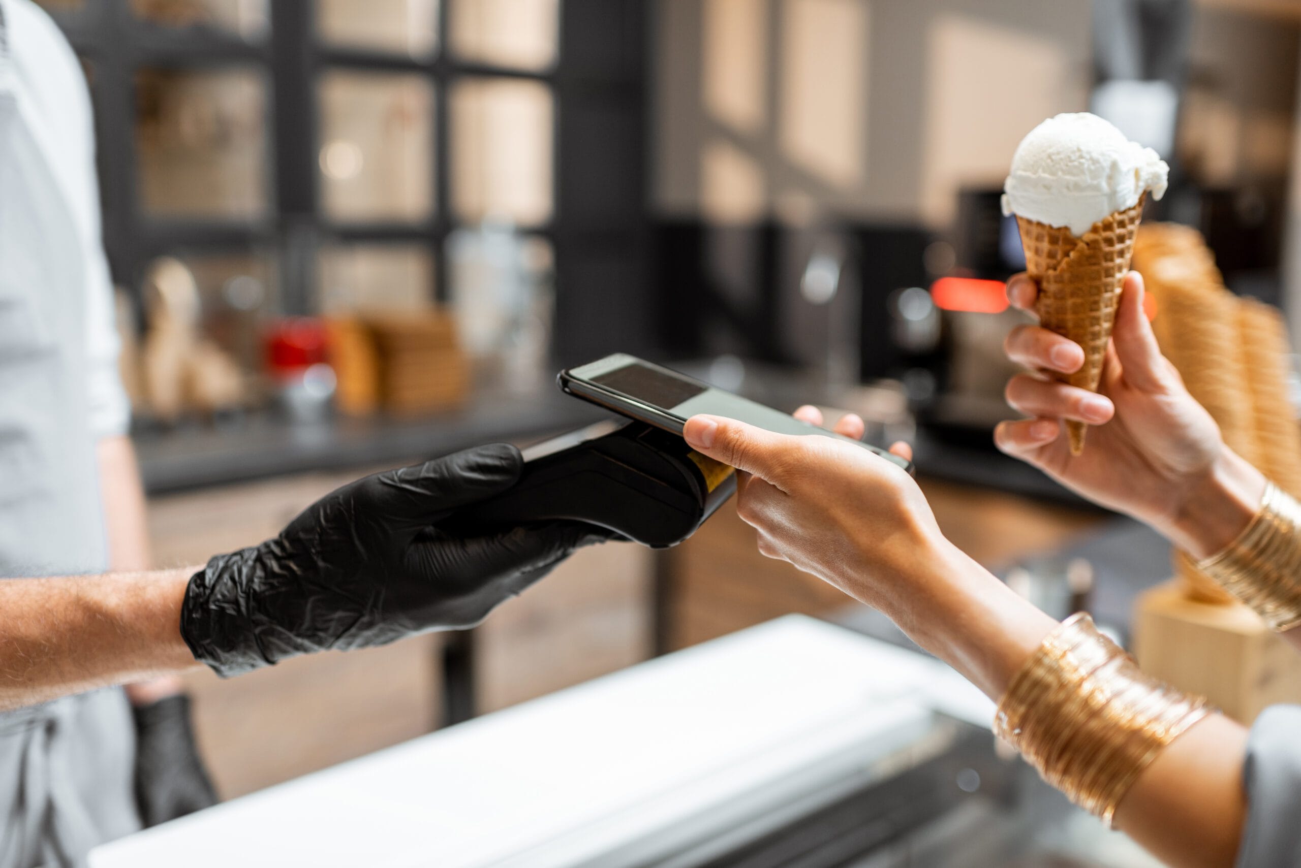 POS integration maximise sales sales revenue maximisation. Seller makes contactless payment for a client in the ice cream shop, close-up